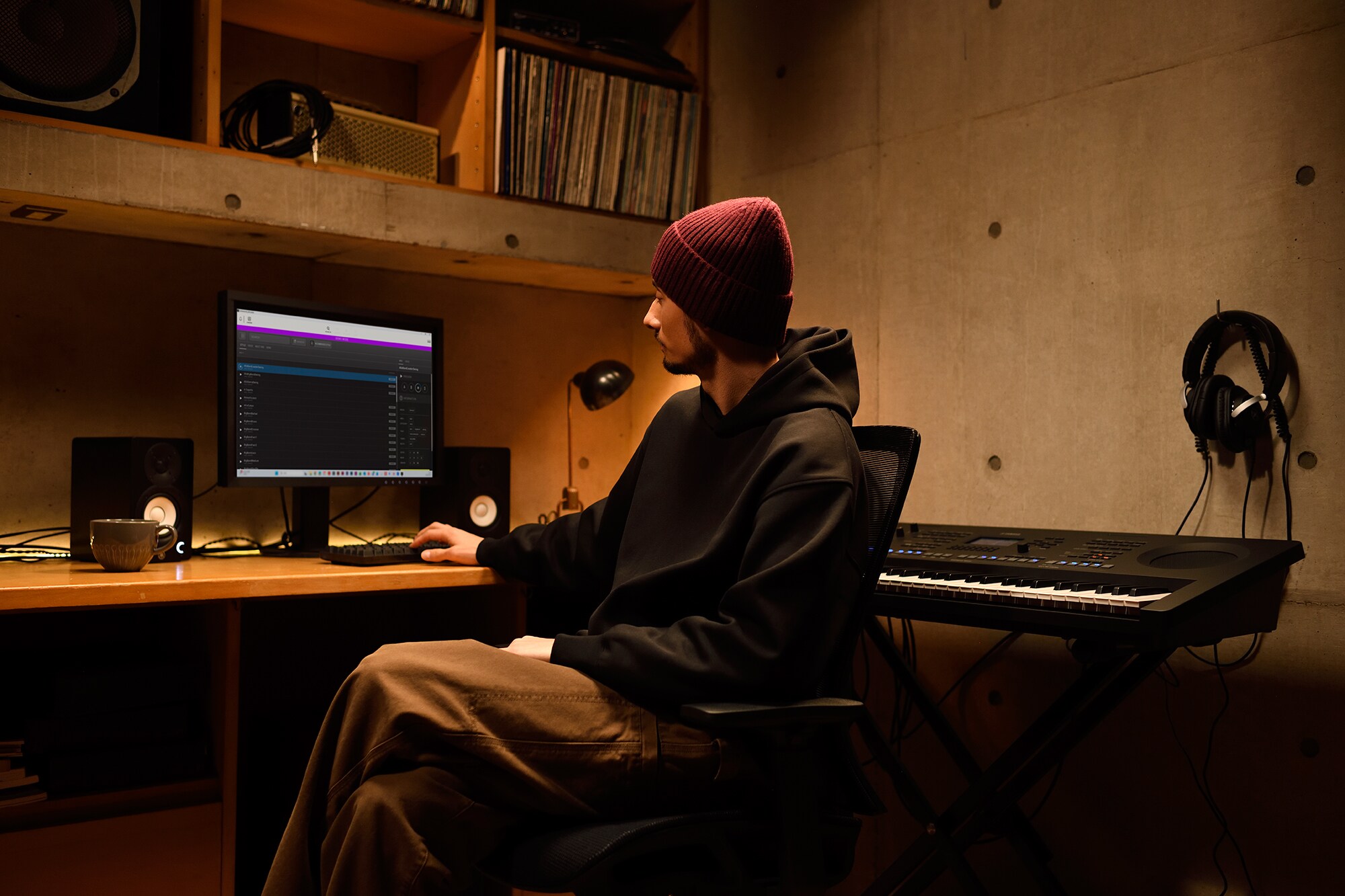 A home music workspace with a computer and keyboard, featuring a keyboardist working in their home studio