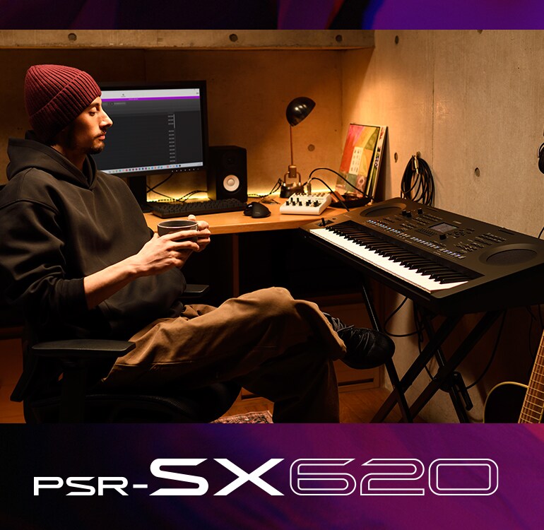 Person sitting at a PSR-SX keyboard in a home studio, drinking coffee.