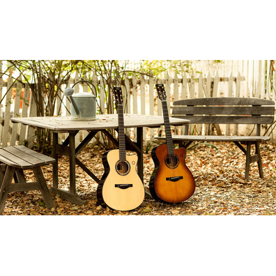 Two acoustic guitars resting by a wooden bench outdoors.
